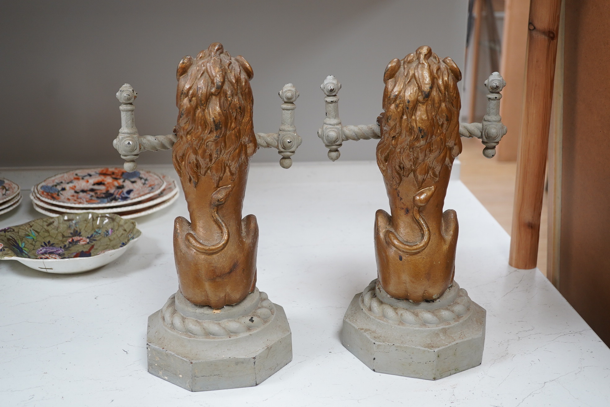 A pair of cast iron fire dogs in the form of triumphant lions, painted, 38cm high, 23cm wide. Condition - fair